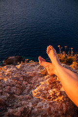 woman legs at the cliff on sunset