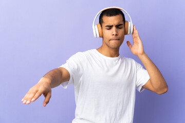 Fototapeta premium African American man over isolated purple background listening music and dancing