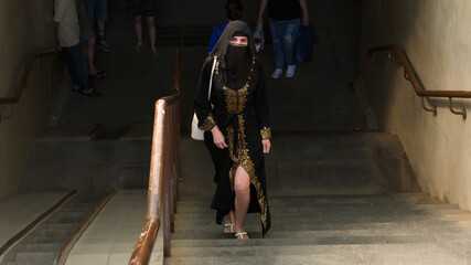 A Muslim woman national dress walks through underground passage.