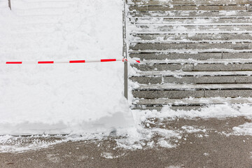 Geräumte Treppe im Winter mit Schnee und Absperrband