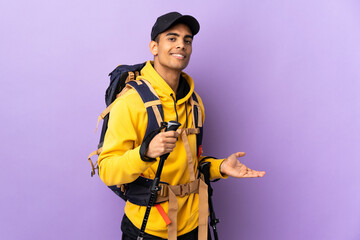African American man with backpack and trekking poles over isolated background extending hands to the side for inviting to come