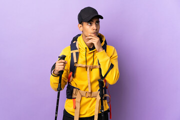 African American man with backpack and trekking poles over isolated background having doubts and with confuse face expression