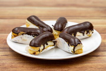 Chocolate eclair cake on wooden background. Traditional french dessert. Pastry products. close up
