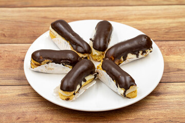 Chocolate eclair cake on wooden background. Traditional french dessert. Pastry products. close up