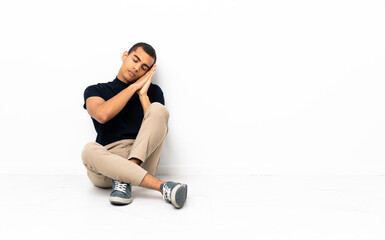 Obraz premium African American man sitting on the floor making sleep gesture in dorable expression