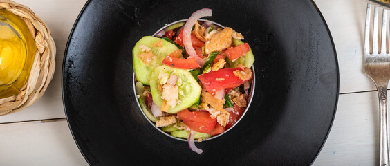 Restaurant serving panzanella salad using cooking ring on black plate