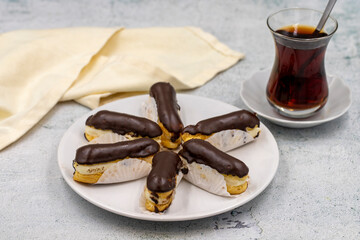 Tasty eclairs and cup of tea on stone table. Traditional french dessert. Pastry products. Close up