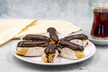 Tasty eclairs and cup of tea on stone table. Traditional french dessert. Pastry products. Close up