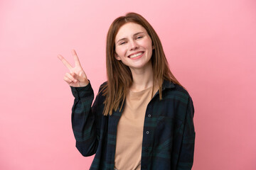 Young English woman isolated on pink background smiling and showing victory sign