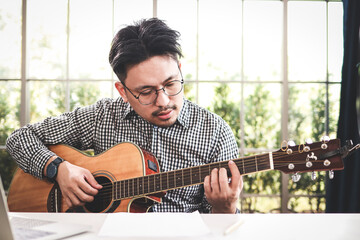 Asian male musician playing guitar in recording studio. playing live music Acoustic music or classical music genre. Solo artist. Songwriter.