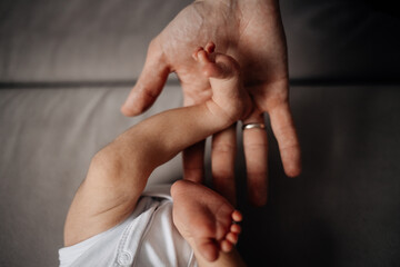 Fototapeta premium Father hold the leg of a newborn baby, trust and care