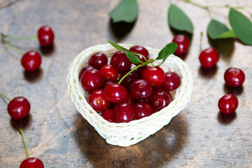 Ripe cherries in a white basket on a brown background.. Close-up. Copyspace.