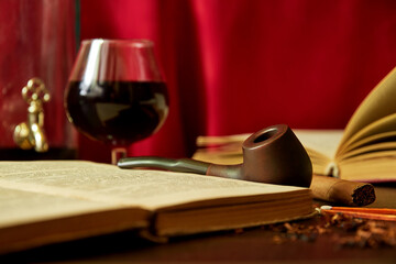 Old man's desk with smoking pipe, tobacco, brandy and books. Luxury cabinet with a relax equipment