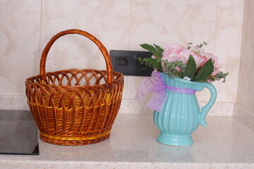 Fototapeta na wymiar blue jar with flowers and wicker basket as kitchen decoration closeup photo