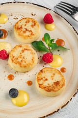 Pancakes with cottage cheese for breakfast. Cheesecakes with fresh raspberries and blueberries on a plate, close-up
