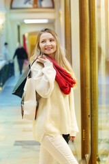 happy blond girl in red scarf hold shopping bag with copy space close up photo on Christmas decorated city background