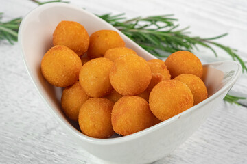 Deep-fried cheese balls filled with parmesan or mozzarella. Baked cheese croquettes, served in a white bowl, close-up