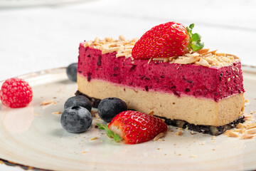 A piece of strawberry mousse cake decorated with fresh berries on a plate. Dessert with strawberry cream