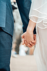 Close up shot of bride and groom in wedding dress holding hands outdoors. Wedding ceremony. Just married concept. 