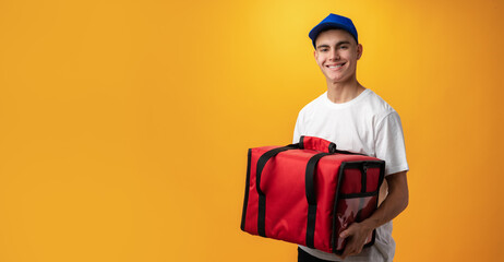 Portrait of pizza delivery boy with thermal bag against yellow background