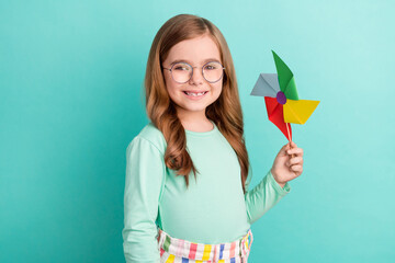 Profile side photo of young little girl happy positive smile paper origami windmill isolated over teal color background