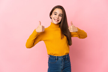 Little girl isolated on pink background giving a thumbs up gesture