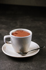 Cup of fragrant sweet hot chocolate on a black background