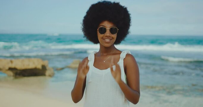 Happy young stylish black woman relaxing at the beach, morning afro beach vibes, happy fashion lifestyle