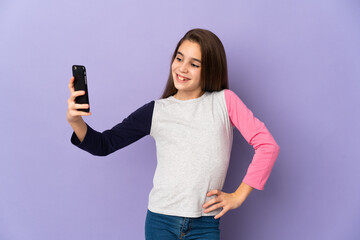 Little girl isolated on purple background making a selfie