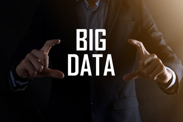 Businessman in a suit on a dark background holds the inscription BIG DATA. Storage Network Online Server Concept.Social network or business analytics representation