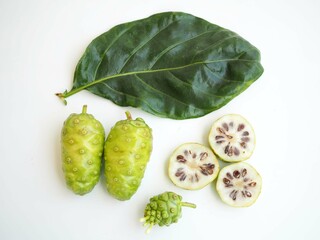 Naklejka premium Fresh Noni or Morinda Citrifolia fruits with sliced and green leaf on white background. top view photo, blurred.