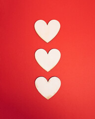 Tree wooden natural hearts centered on bright red background. Sharing valentine getting in love atmosphere. Minimal flat lay concept for holiday romance.