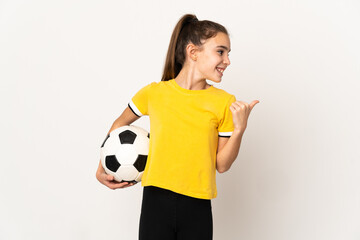 Little football player girl isolated on white background pointing to the side to present a product