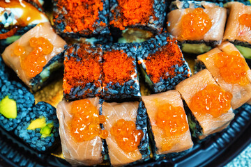 a set of rolls with black rice on a round plastic dish. cuttlefish ink. 