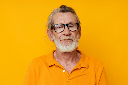 an elderly man with glasses in a yellow t-shirt with glasses close-up