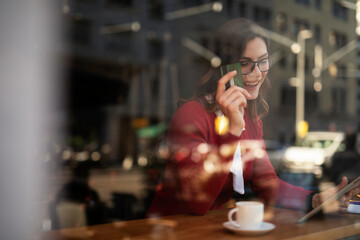 Happy woman using credit card to shopping online with tablet. Beautiful young woman drinking coffee in cafe.