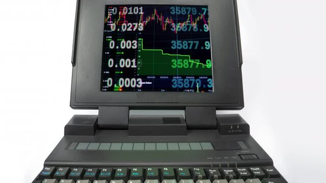 Vintage laptop spinning with stock trading on screen