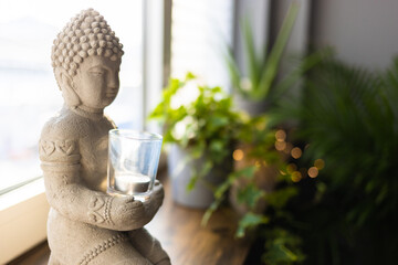 Buddha statue close-up in beautiful light. Close up of a Buddha figurine. Modern decor on a shelf,...