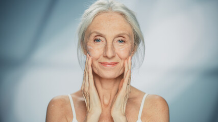 Portrait of Beautiful Senior Woman Gently Applying Face Cream. Elderly Lady Makes Her Skin Soft,...