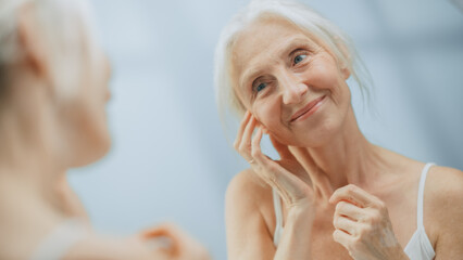 Beautiful Senior Woman Looks into Bathroom Mirror Touches Her Neck, Happily Smiles, Enjoy Her Looks...