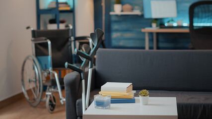 Nobody in living room with walking support equipment. Wheelchair and crutches used by person with physical disability to help with accessibility and transportation. Recovery objects