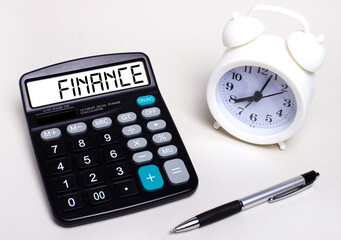 On the light table there is a black calculator with the text FINANCE on the scoreboard, a pen and a white alarm clock. Business concept