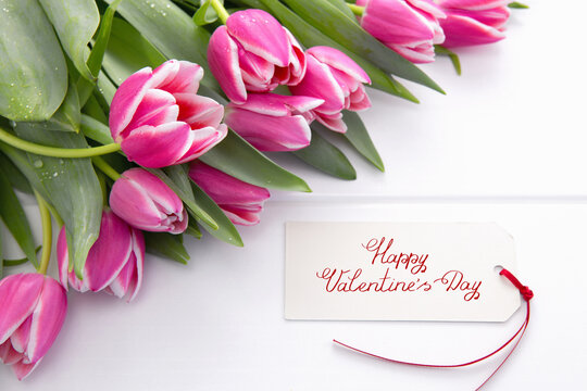 Valentine's Day card and a bouquet of beautiful tulips on wooden background.