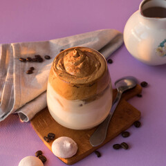 Dalgona coffee on a very peri color, tea spoon, milk jug and roasted coffee beans . Korean drink with coffee foam.   Color of the year 2022.  Dalgona coffee on a violet background . Trendy beverage
