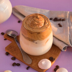 Dalgona coffee on a very peri color, tea spoon, milk jug and roasted coffee beans . Korean drink with coffee foam.   Color of the year 2022.  Dalgona coffee on a violet background . Trendy beverage