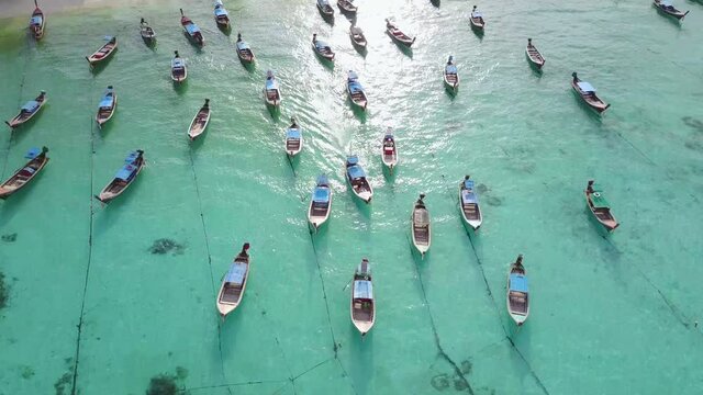 Aerial view of stunning summer landscape. A group of fishing long tail boat in turquoise Andaman sea and white sand beach at Koh Lipe or Lipe island, Satun, Southern Thailand. 4K drone video