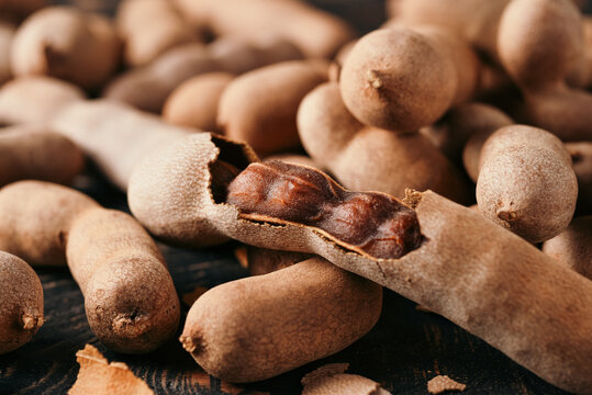Fresh Tamarind fruits (Tamarindus indica, Indian date) Sweet ripe tamarinds on dark wood background. close-up