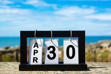 Apr 30 calendar date text on wooden frame with blurred background of ocean