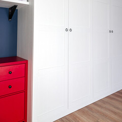 The interior of the apartment in the Scandinavian style. White wardrobe, red dresser and blue wall....