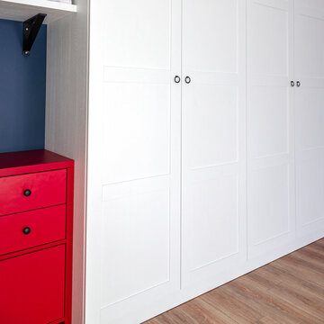 The interior of the apartment in the Scandinavian style. White wardrobe, red dresser and blue wall. Custom furniture